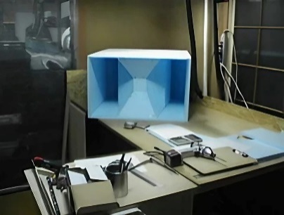 A blue horn cabinet prototype on a workbench beside rulers and measuring tools.